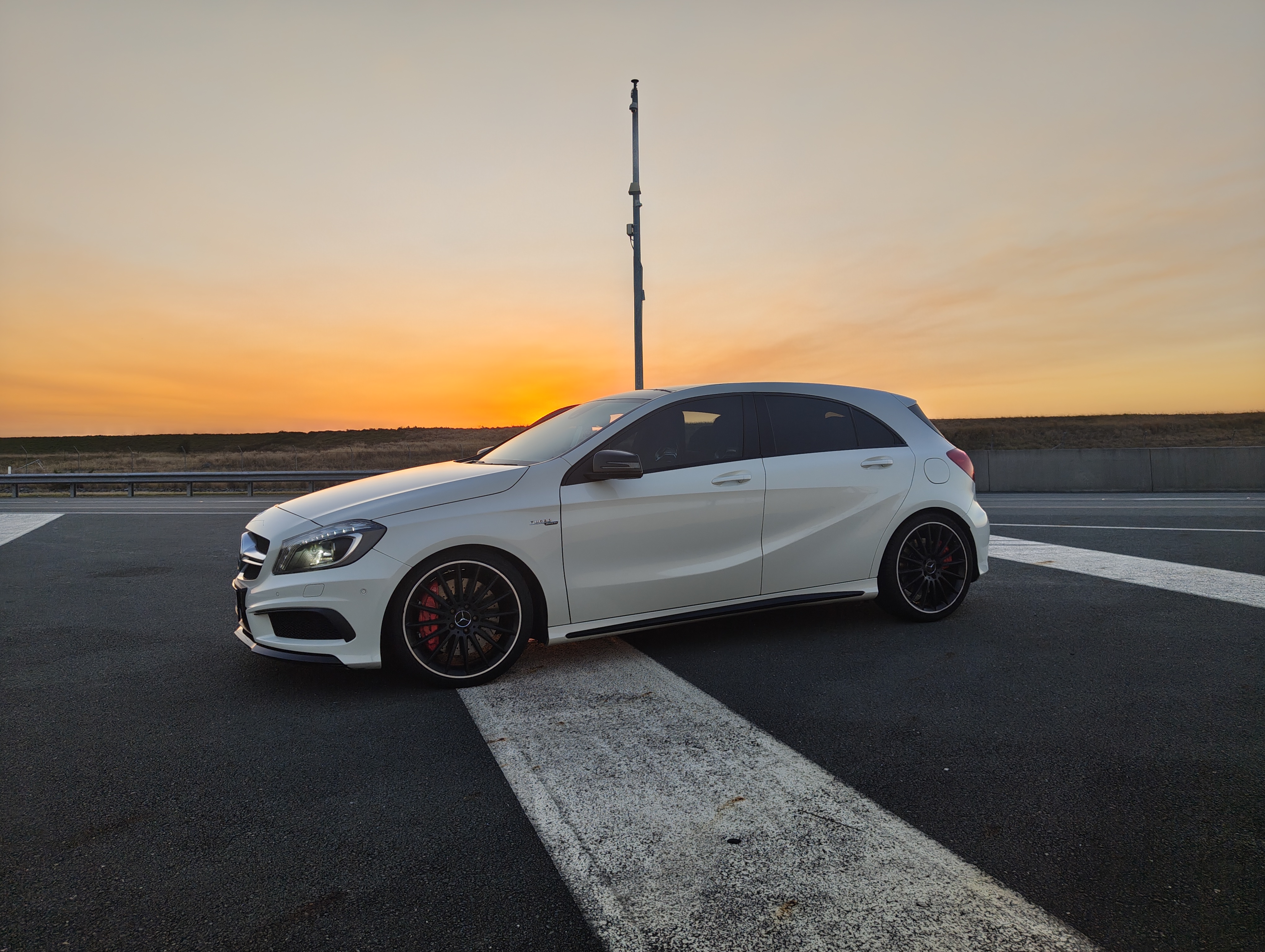 White Mercedes performance hatchback at sunset